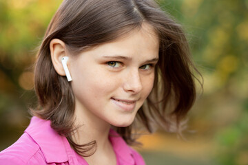 Beautiful young girl enjoy listening to music with wireless headphone with good mood and relax outdoor. 