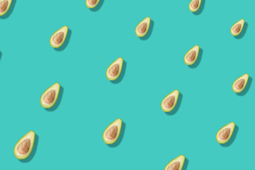 Colorful pattern of fresh avocados on turquoise background with shadows. Top view. Flat lay. Pop art design