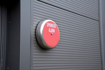 A bell located in an industrial hall. reports the launch of sprinklers extinguishing a possible fire inside an industrial plant. inscription on a circular sprinkler alarm bell