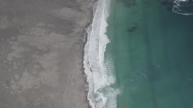 Aerial view overlooking waves hitting the Bunes beach, in dark, cloudy Lofoten, Norway - high angle, drone shot