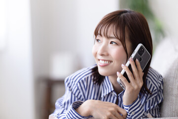 ソファに寝転んで電話する女性