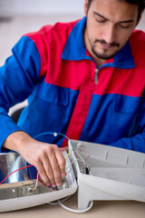 Young male repairman repairing heater