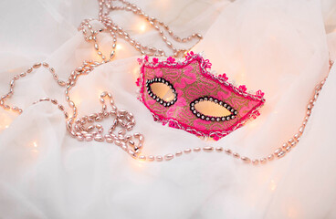 Traditional carnival mask Mardi gras pink beads on a white background. Venetian masks. An...