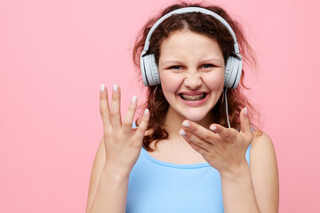 cheerful woman with headphones music posing pink background