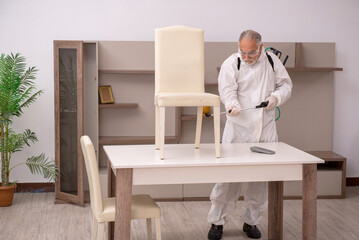 Old male contractor doing pest control at home