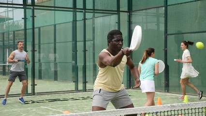 Portrait of young adult man paddle tennis player performing basic strokes at court during group training. High quality 4k footage