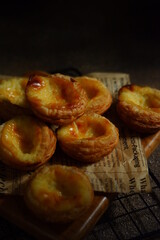 pile of egg tarts in a wire cooling rack against dark background  