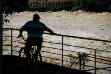 A man on his bike looks on the high level waters of Piracicaba river during a severe flood in the...