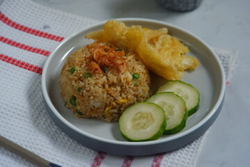 a plate of fried rice  served with cucumber slices and fried egg