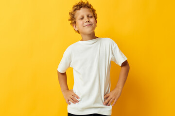 boy with curly hair in a white t-shirt on a yellow background