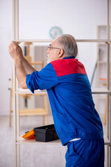 Old male carpenter working indoors