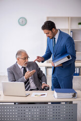 Fototapeta premium Old male boss and young male employee working in the office