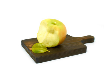 A bitten green apple and a small green leaf lie on a wooden cutting board