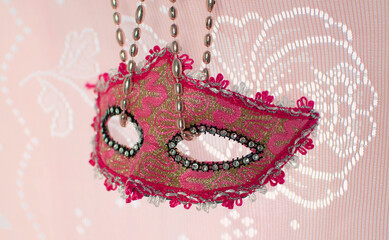 festive, colorful Mardi Gras or carnival mask and beads on a pink background. Venetian masks. An invitation to a party, a greeting card, the concept of celebrating the Carnival of Venice