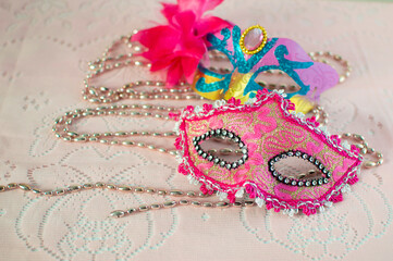 festive, colorful Mardi Gras or carnival mask and beads on a pink background. Venetian masks. An...
