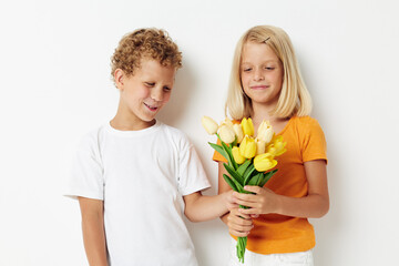 Fototapeta na wymiar two joyful children with a bouquet of flowers gift birthday holiday childhood light background