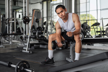 Asian man exercises in fitness. Fit man doing bicep curl exercises in gym.