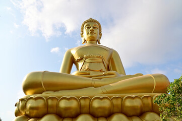 The Big Golden Buddha Statue with blue sky and white cloud in Buddhist temples in Bangkok, Thailand. Concept for those who have faith to come to pay respect.