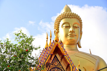 Obraz premium The Big Golden Buddha Statue with blue sky and white cloud in Buddhist temples in Bangkok, Thailand. Concept for those who have faith to come to pay respect.