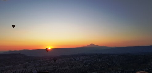 Fototapeta premium sunrise in the mountains under air ballons