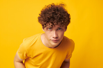 Fototapeta na wymiar Young curly-haired man yellow t-shirt glasses fashion hand gestures yellow background unaltered