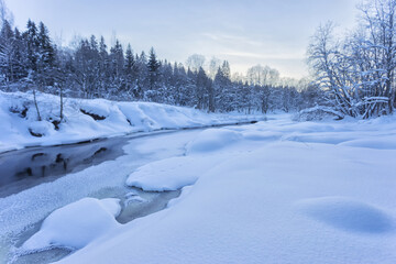 Snow banks of forest river at winter sunset. Winter landscape