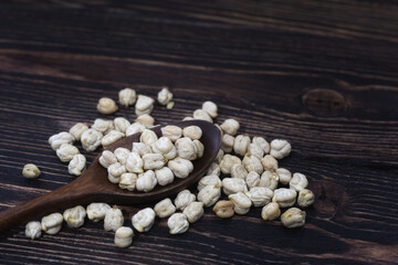 Chickpeas in a wooden spoon on a dark wooden background