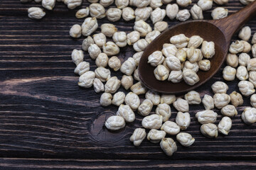 Chickpeas in a wooden spoon on a dark wooden background