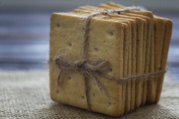 A stack of crackers tied with string on sackcloth. Close-up of crispy, ready-to-eat crackers. 