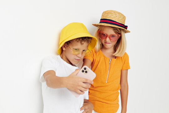 Cheerful boy and girl in fashionable glasses hats selfie posing