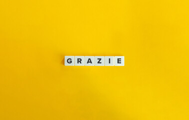 Grazie Word on Letter Tiles on Yellow Orange Background. Minimal aesthetics.