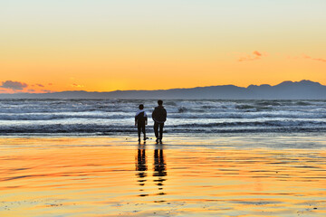 Fototapeta premium 片瀬西浜海岸の夕陽と波打ち際で遊ぶ子供たち