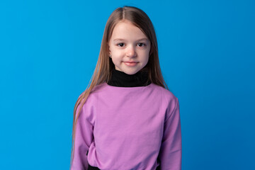 Portrait of a little smiling girl preteen on blue background