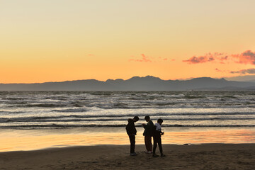 片瀬西浜海岸の夕陽と波打ち際で遊ぶ子供たち