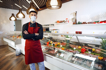 Portrait of a young man shopkeeper standing by meat stall in supermarket