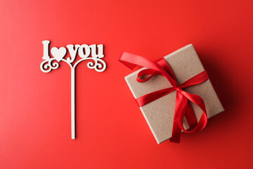 Flat lay gift box and a sign with the words I love you on a red background. The concept of Valentine's Day.