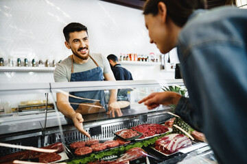 Butcher's shop seller helps to choose product to woman customer