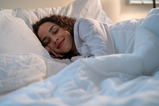 Latino beautiful woman lying down on bed in bedroom in dark night room