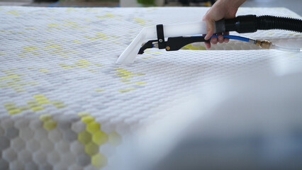 Male Worker Cleaning a mattress With Vacuum Cleaner.Professionally extraction method. Upholstered...