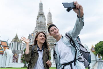 Asian couple backpacker using camera selfie and take a picture in city