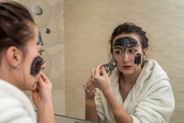 young cute brunette makes a gorgeous clay black mask from pimples and blackheads.