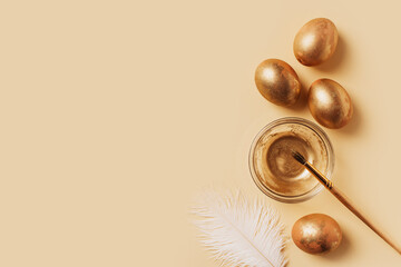 Happy easter concept with gold eggs, feather and colors on yellow and beige background