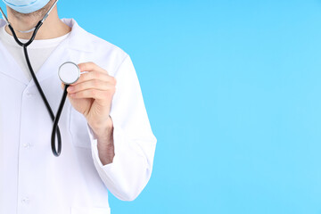 Young man doctor with stethoscope on blue background