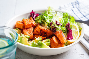 Baked sweet potato slices with avocado and green salad. Healthy vegan food concept.