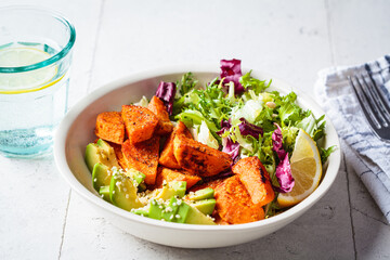 Baked sweet potato slices with avocado and green salad. Healthy vegan food concept.
