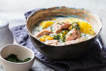 Norwegian fish soup with trout, potatoes and corn, gray background.