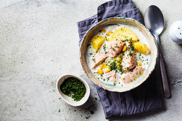 Norwegian fish soup with trout, potatoes and corn, gray background.