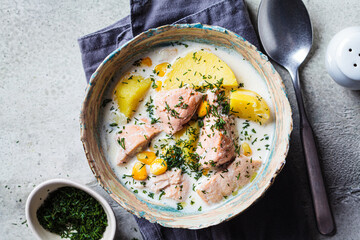 Norwegian fish soup with trout, potatoes and corn, gray background.