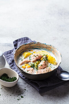 Norwegian fish soup with trout, potatoes and corn, gray background.