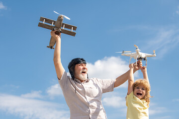 Grandfather and grandson with toy plane and quadcopter drone against sky. Child pilot aviator with plane dreams of traveling. Family Relationship Grandfather and child.